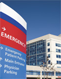 Blue and red hospital wayfinding sign showing directions to the emergency room, main entrance, and parking.