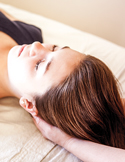 Close-up of a person lying down receiving a Reiki healing treatment with hands cradling their head.