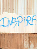 Activism The word "INSPIRE" spray-painted in blue on a weathered, corrugated metal wall.