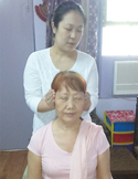 A woman performing a Reiki head position healing session on another seated woman.