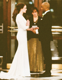 A bride and groom standing before an officiant during a wedding ceremony in an elegant indoor setting.