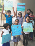 A group of smiling children holding up colorful, handmade paper art projects and drawings.
