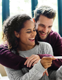 A happy man and woman smiling together while looking at a positive pregnancy test.