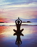 Silhouette of a person in a yoga pose on a beach at sunset with a vivid reflection on the wet sand.