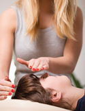 A practitioner performs a Reiki session by hovering their hands over a client's forehead.