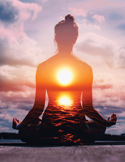 Silhouette of a person in a yoga pose with a glowing sunset and ocean landscape overlaid on their body.