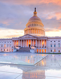 The U.S. Capitol Building at sunset with a glowing dome and reflective foreground.