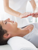 Close-up of a Reiki practitioner’s hands hovering over a woman’s head during a healing session.