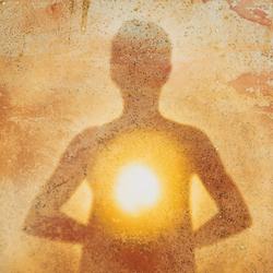 Silhouette of a person with a glowing light at their chest against a warm, textured background, symbolizing inner healing and spiritual energy.