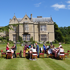 Students practicing Reiki on a sunny lawn in front of the Glastonbury Abbey House.