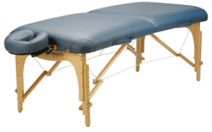 Portable massage table with a light blue padded surface, wooden frame, and an adjustable face cradle.
