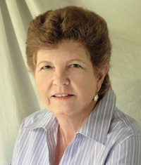 Woman with short brown hair, wearing a striped shirt, smiling at the camera.